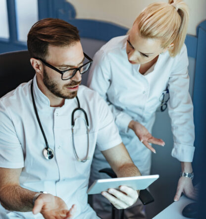 Male doctor and nurse examining medical records on touchpad and communicating in the hospital.
